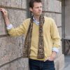 Mann mit schickem Herrenschal von il-Design und einem passenden gelben Pullover vor einer Hausmauer